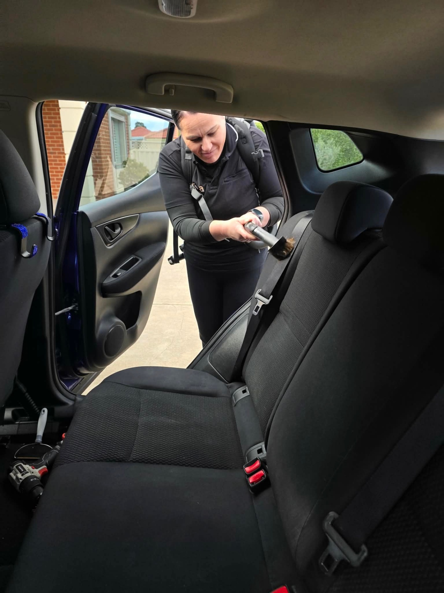 Rear seatbelt and upholstery vacuuming during a professional car detail