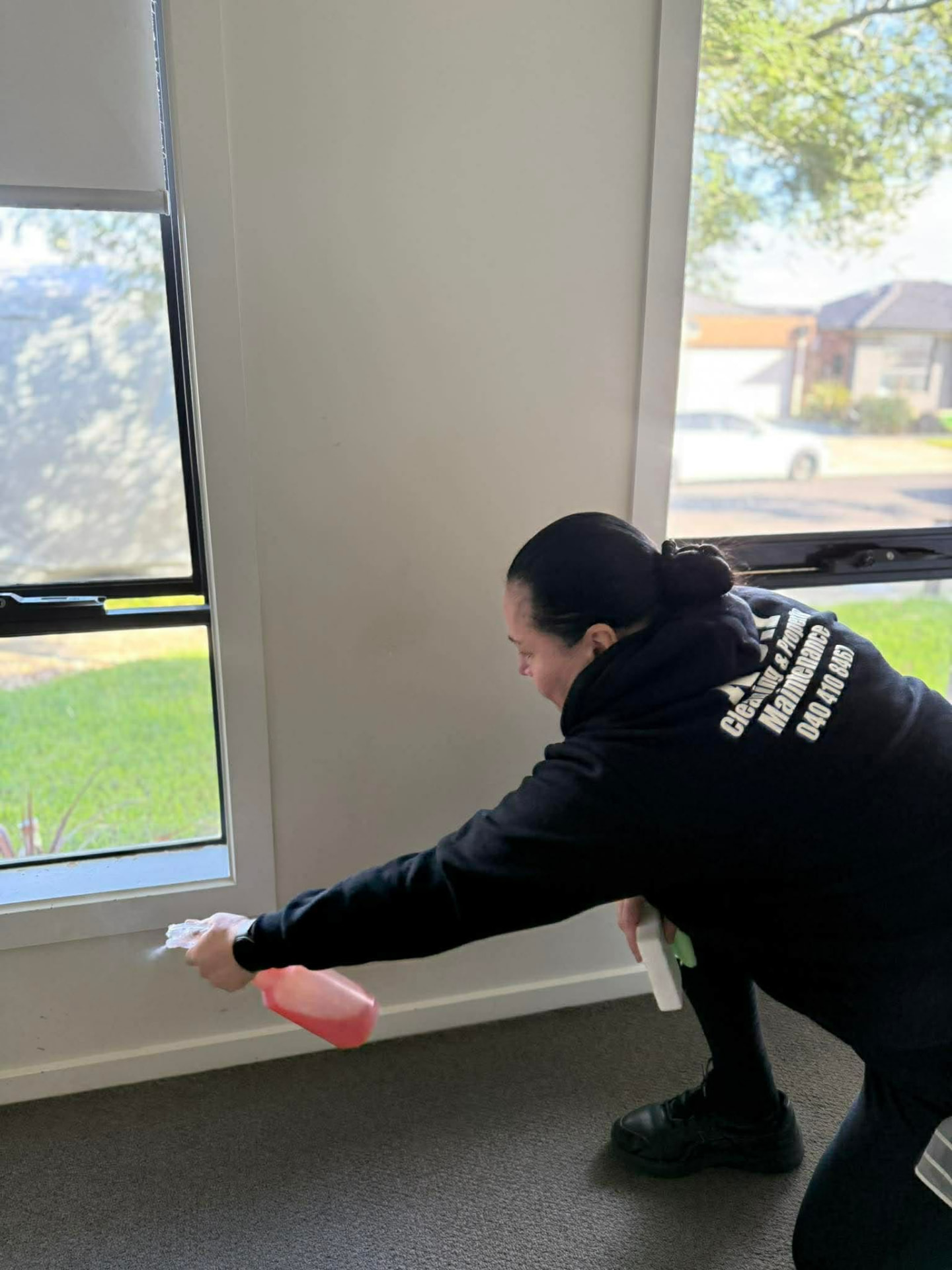 No.1 Cleaning team member spraying and cleaning an interior window frame